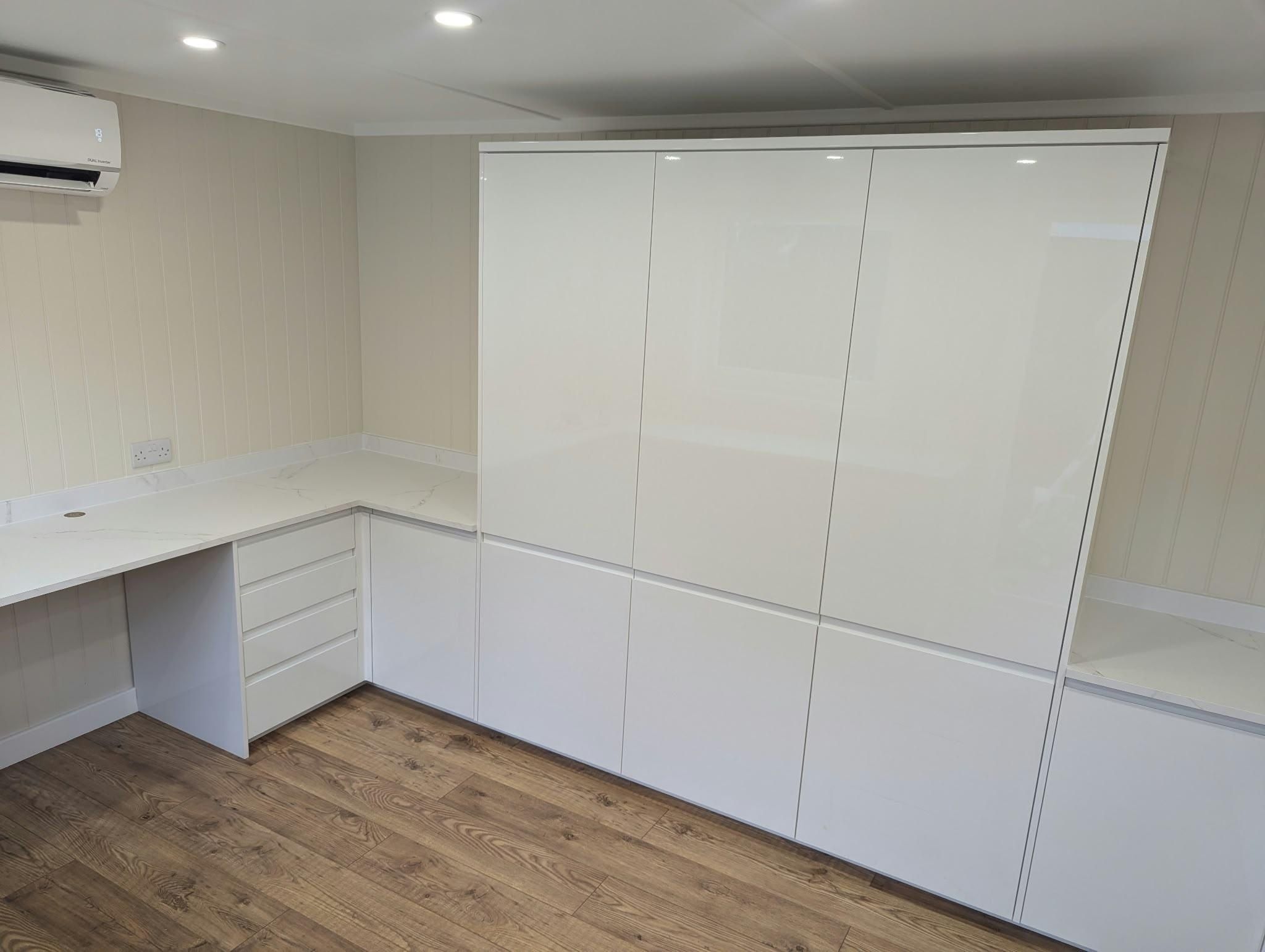 White gloss fitted units with a built-in desk and worktop