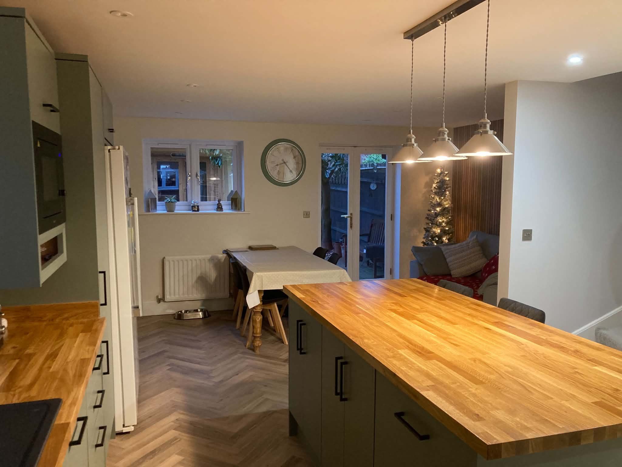 An open-plan kitchen with an oak-topped island looking through to the dining table