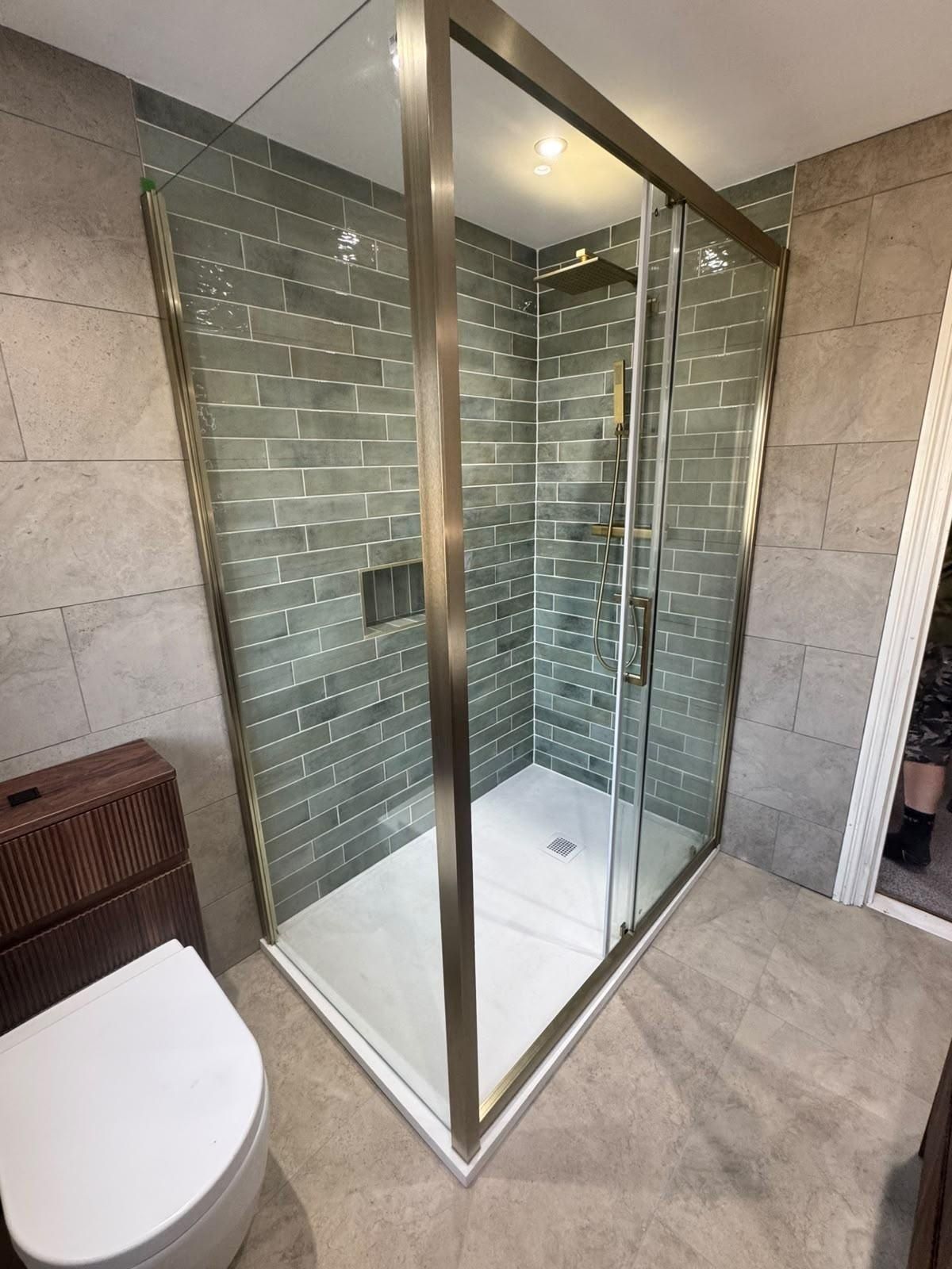 A finished Kaye Co bathroom: green-tiled shower with a brushed brass enclosure