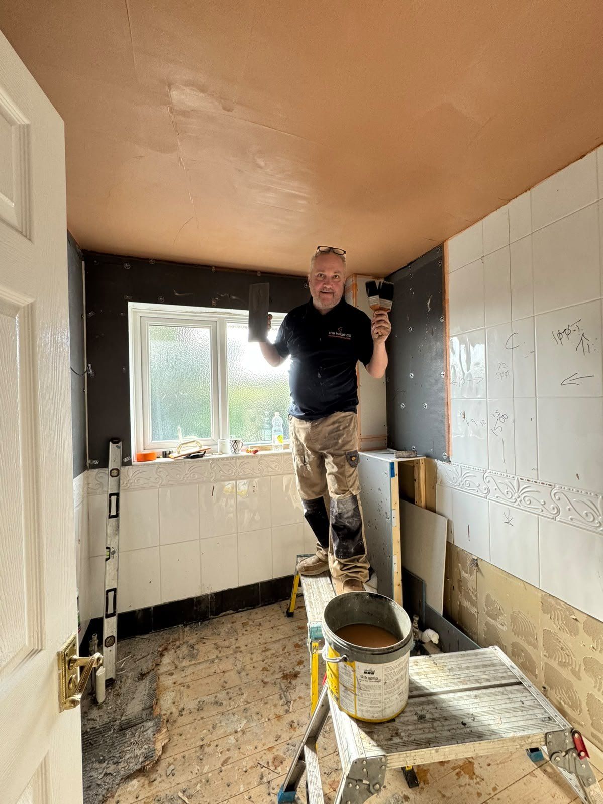 A member of the team priming the walls in a stripped-out bathroom